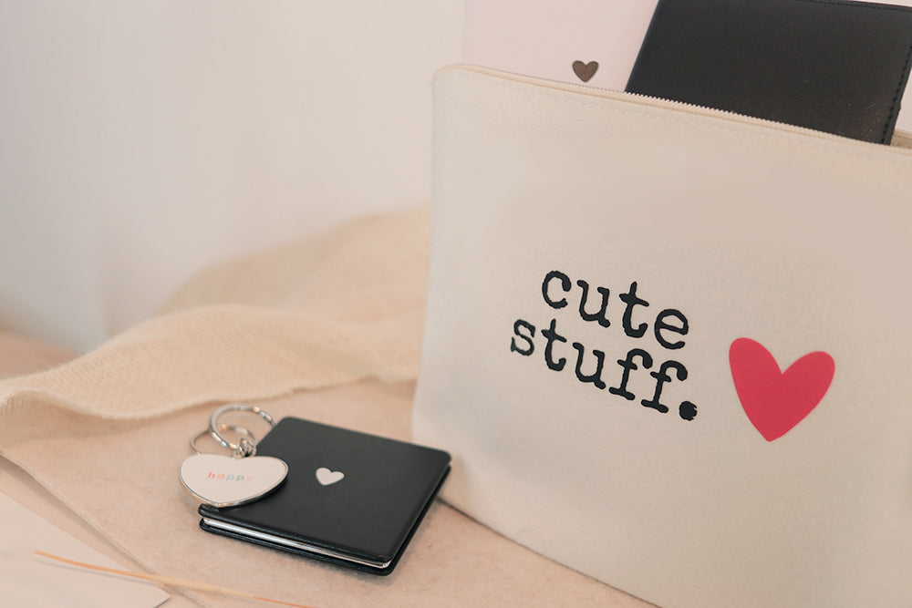 ALEBRI accessory section showcasing a black pocket mirror with a white heart in the middle, a charm with the text "happy on it", a pouch with the text "cute stuff" and a heart next to the text